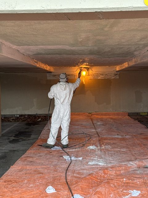 Crew member spray coating a parkade ceiling