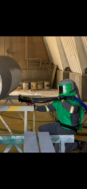 Crew member in a blast hood working in the shop